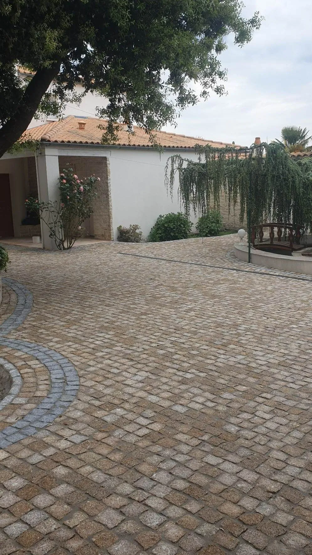 Cour en pavés granit doré avec courbe en granit gris devant une maison de caractère